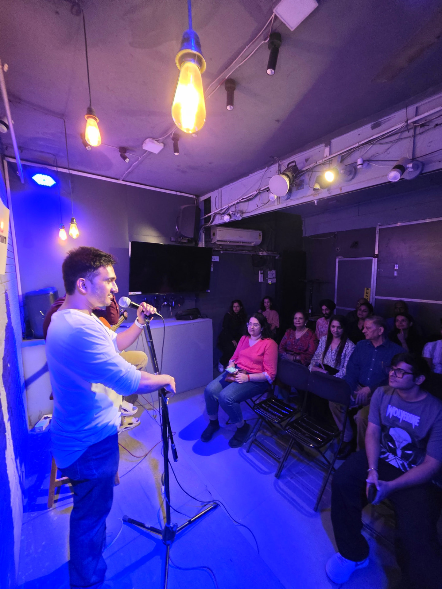 Singer performing with a mic under stage lights at a Music Jammin night