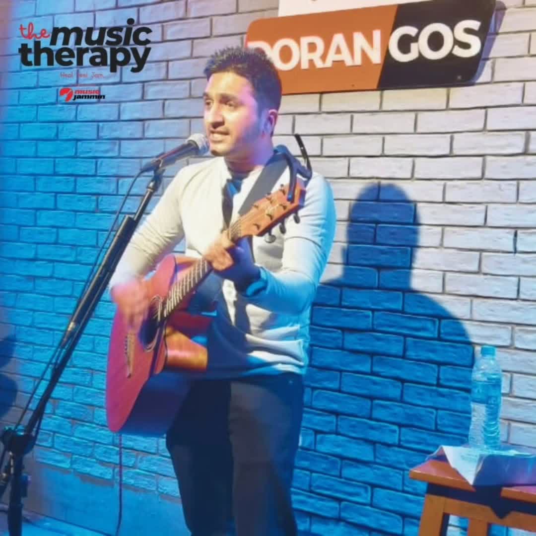 Guitarist singing against a blue brick wall at a Music Therapy show